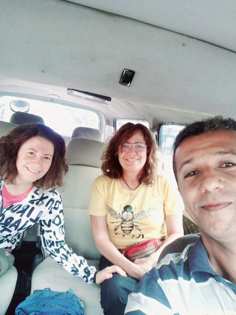 Tour guide taking a relaxed selfie with guests inside the van
